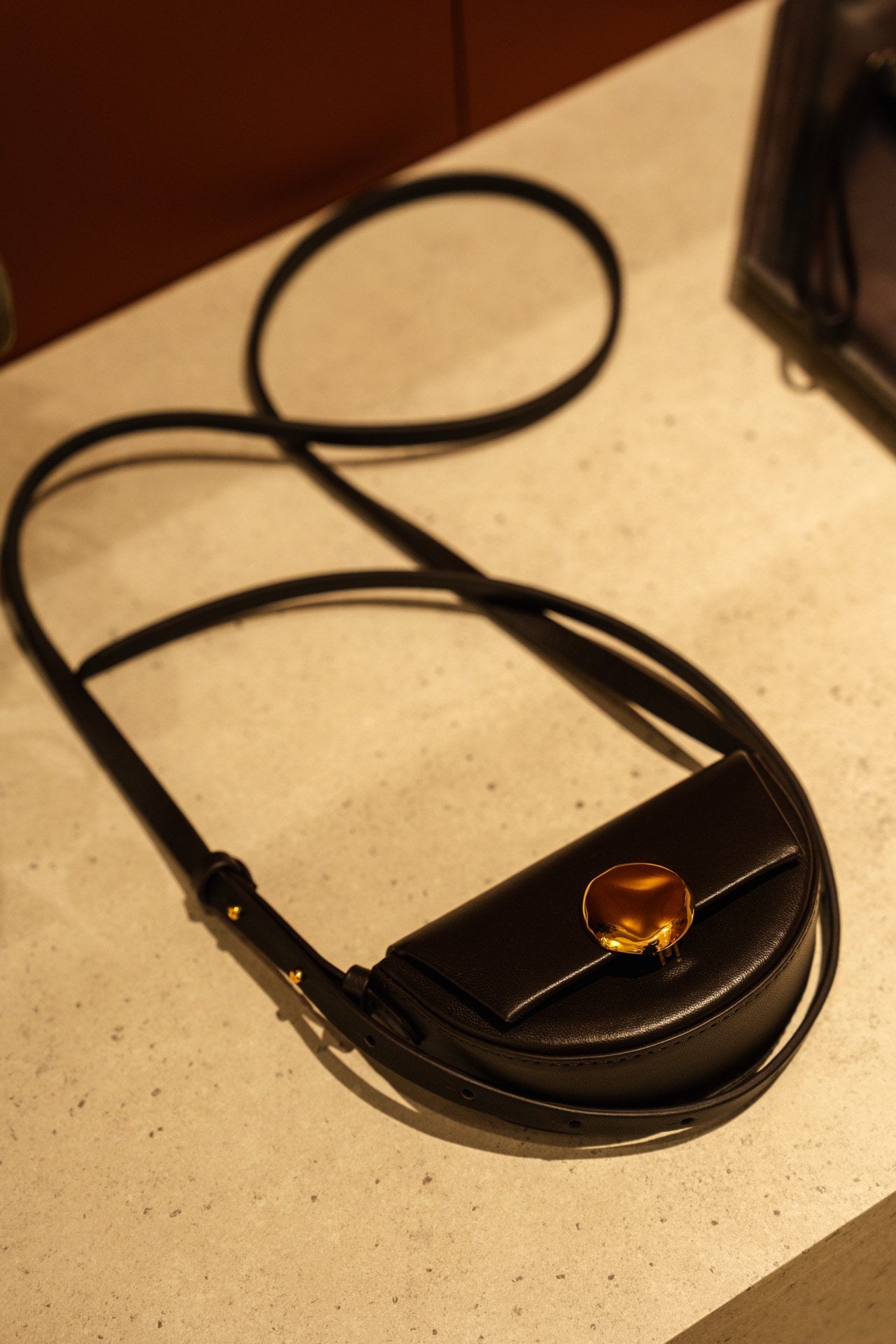 ゴールドの留め具がアクセントのハーフムーン型ミニバッグ