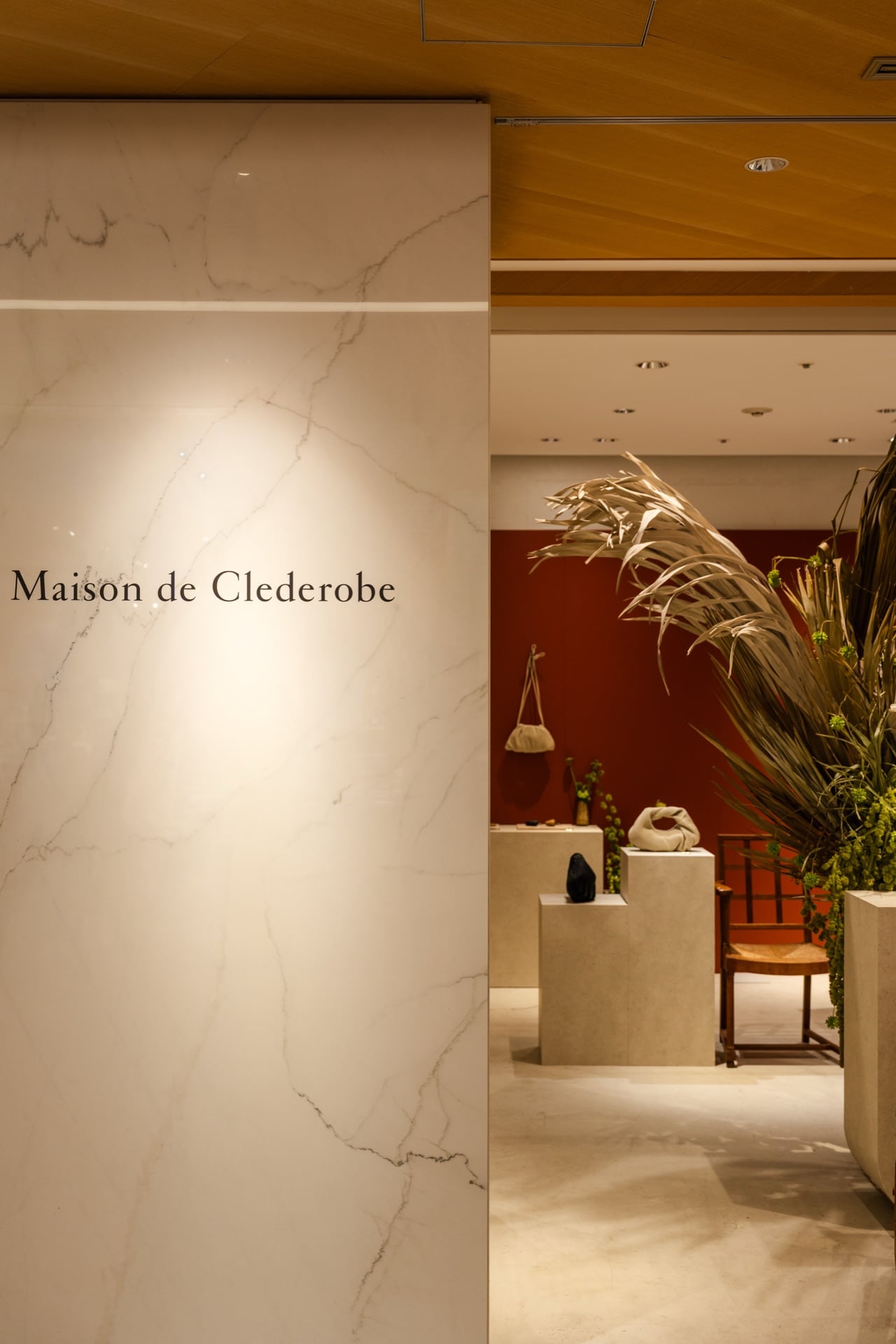 Maison de Clederobe POP UPの店内。大理石の壁に店名が記され、ディスプレイとチェアが静かに並ぶ