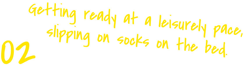 Getting ready at a leisurely pace, slipping on socks on the bed.
